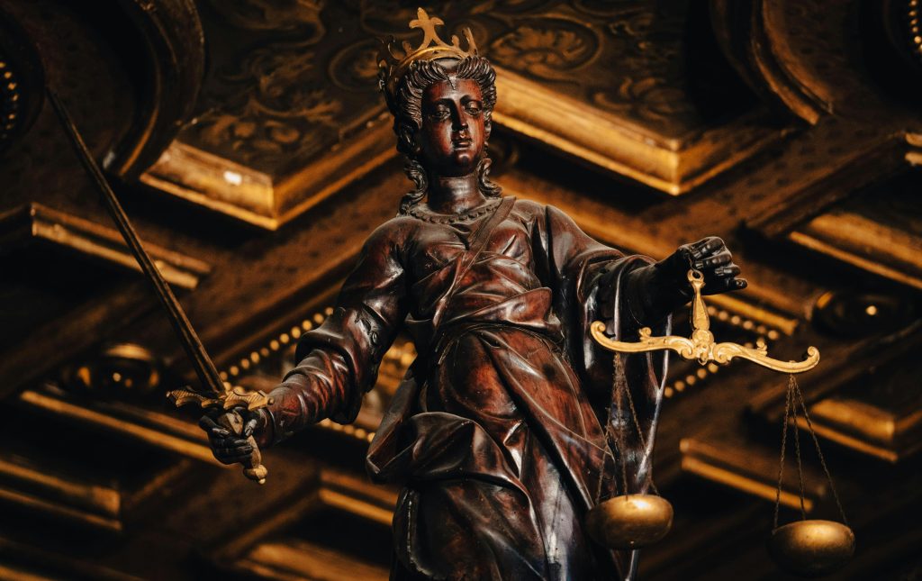 Detailed statue of Lady Justice holding scales and sword indoors with rich textures.